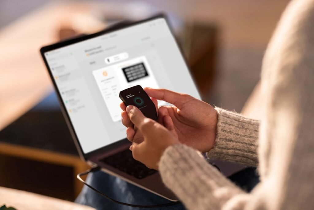 Trezor Safe 5 hardware wallet confirming a cryptocurrency transaction while connected to a laptop for secure self custody